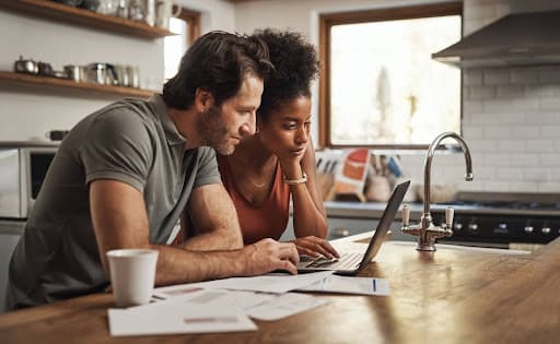 A couple at a kitchen island looking at a property tax loan application on a computer